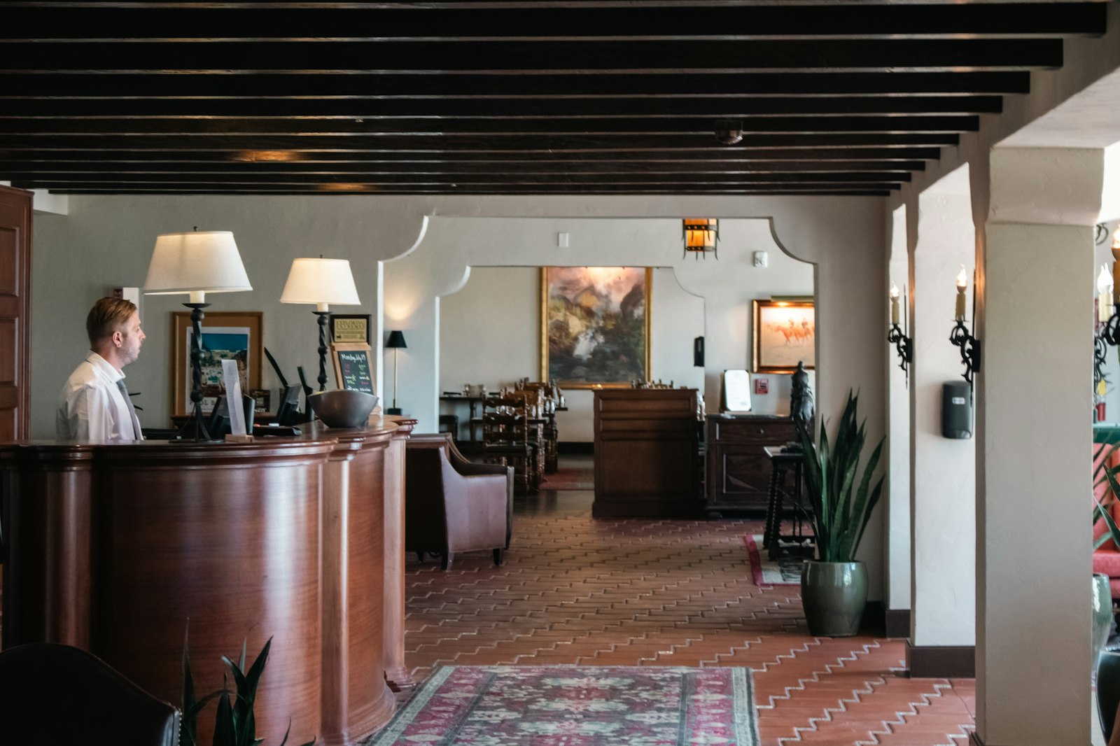 Advisor standing at a warm wood-panelled hotel front desk in a quiet lobby
