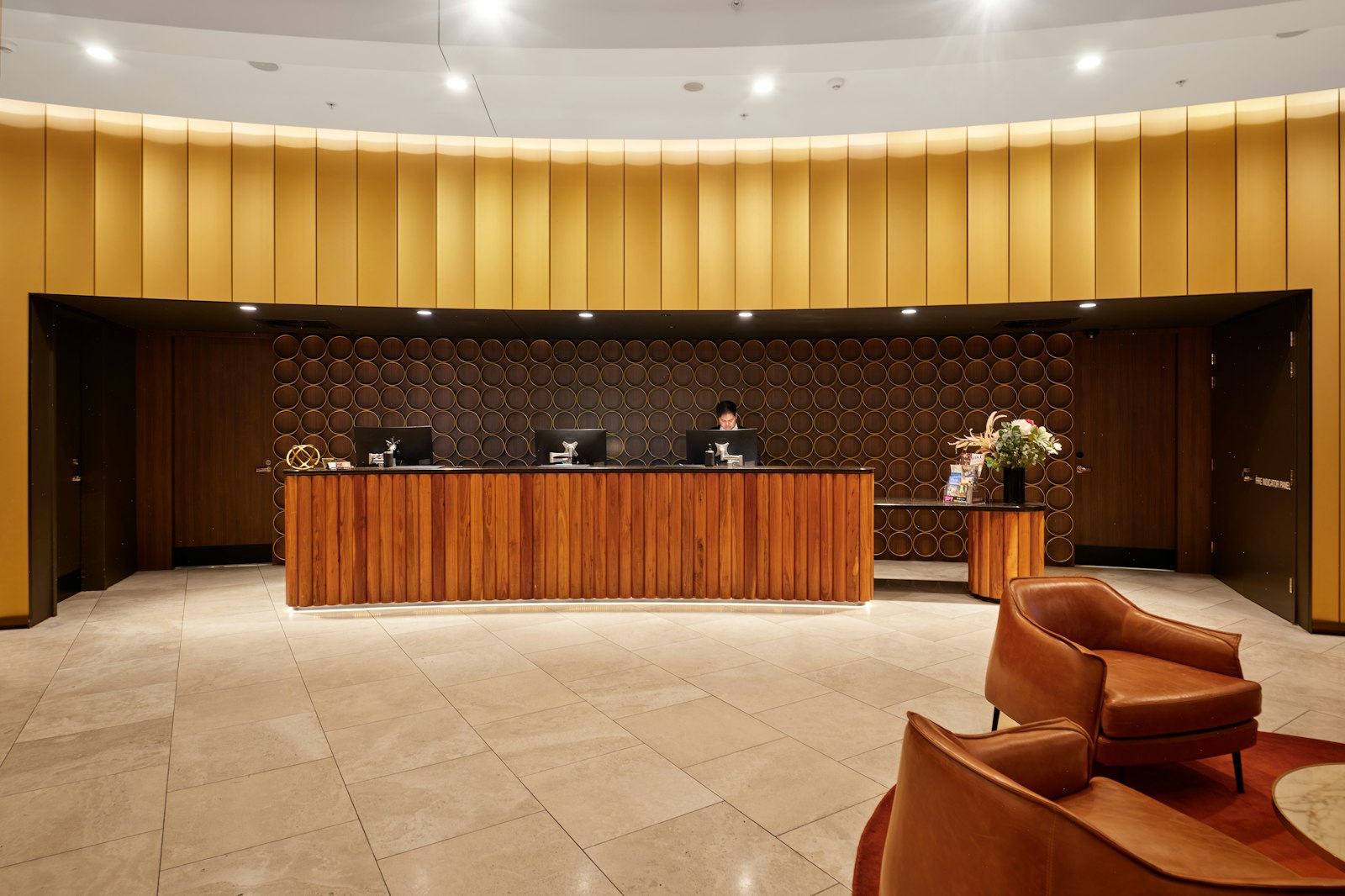 Quiet hotel reception desk under a curved, warmly lit lobby ceiling